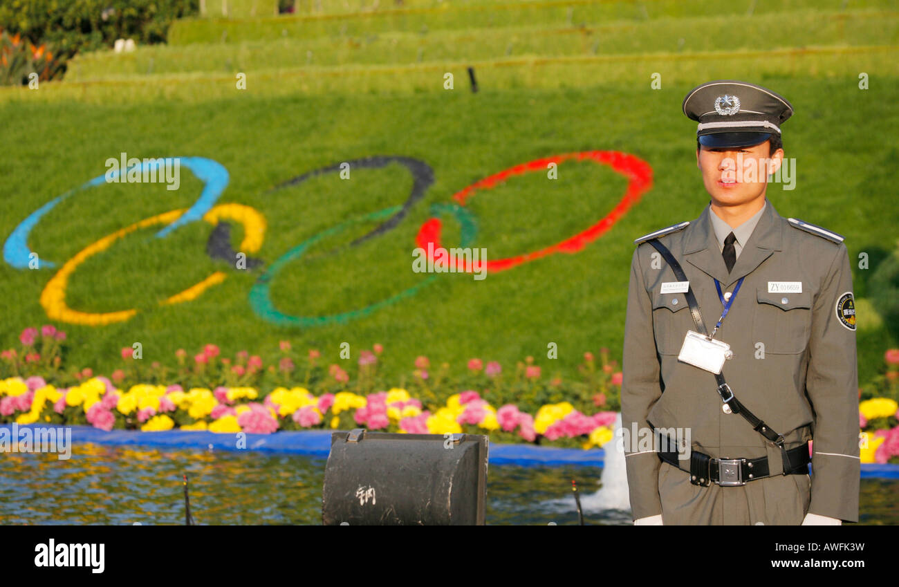 Chinesische Wache mit Olympischen Ring unter dem Motto Blumen im Hintergrund Stockfoto