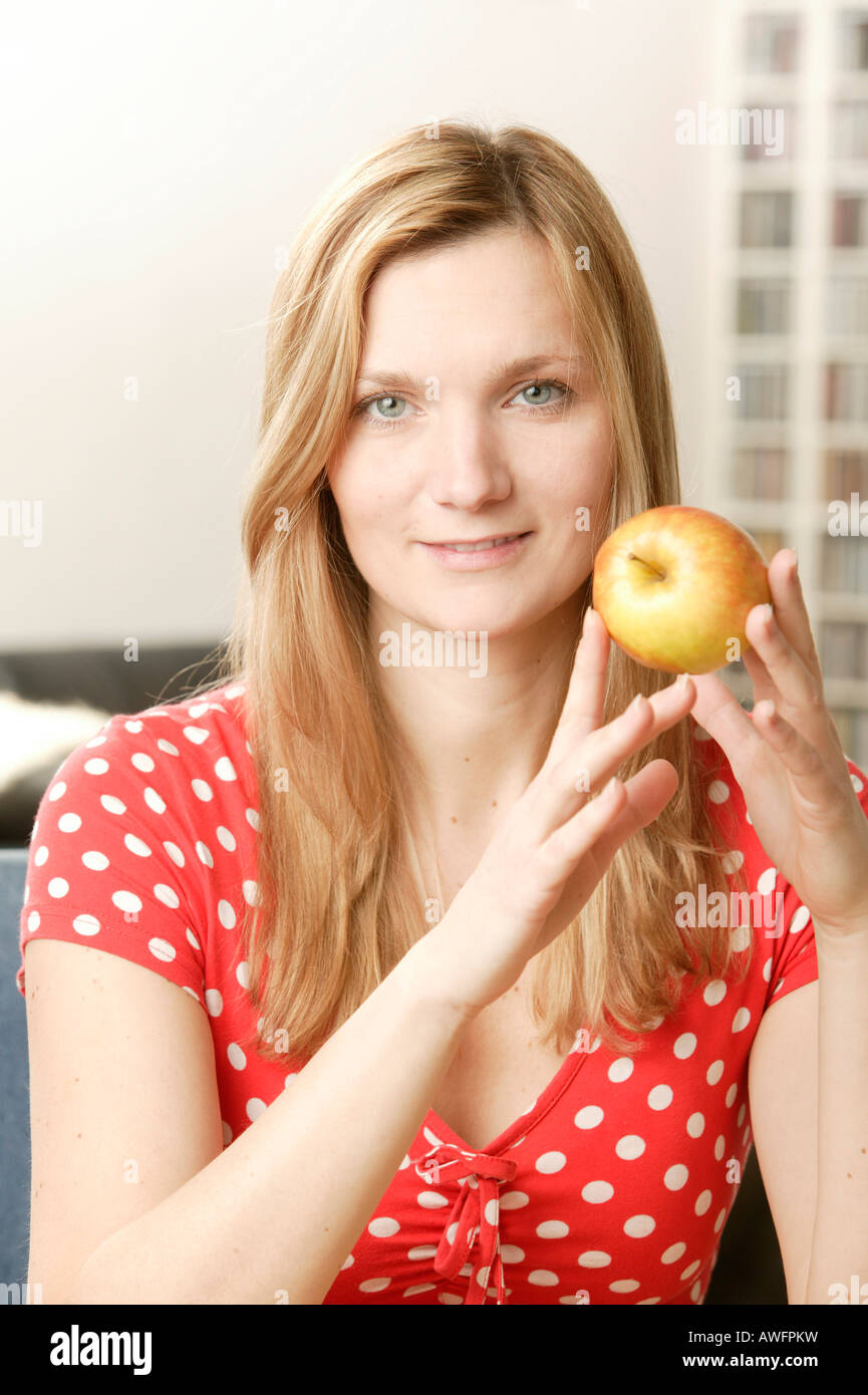 Junge blonde Frau hält einen Apfel Stockfoto