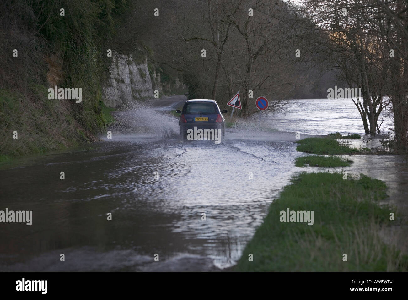 Auto getrieben durch Hochwasser auf einer Straße angrenzend an eine große, schnell fließenden und geschwollenen Fluss, der seine Banken gebrochen hat. Stockfoto
