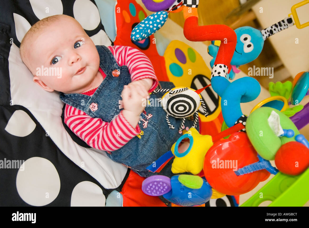 Horizontale Porträt von einem netten kaukasischen Baby Mädchen liegend auf einer bunten Baby Playgym Matte entwickeln ihre Sinne zu stimulieren. Stockfoto