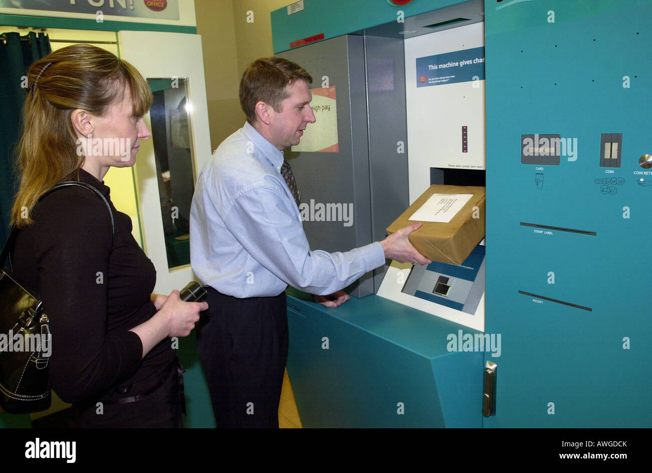 Ein Post-Offizier zeigt ein Mitglied der Öffentlichkeit wie eine automatische Paketautomaten verwenden Stockfoto