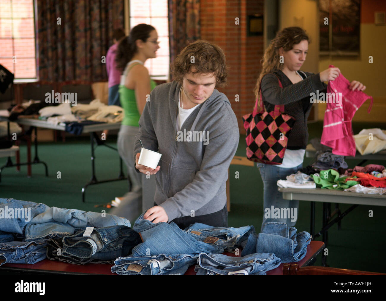 Ein junger Mann inspiziert ein paar Denimjeans in einer Kleidung Swap an der University of Puget Sound in Tacoma, WA, USA. Stockfoto