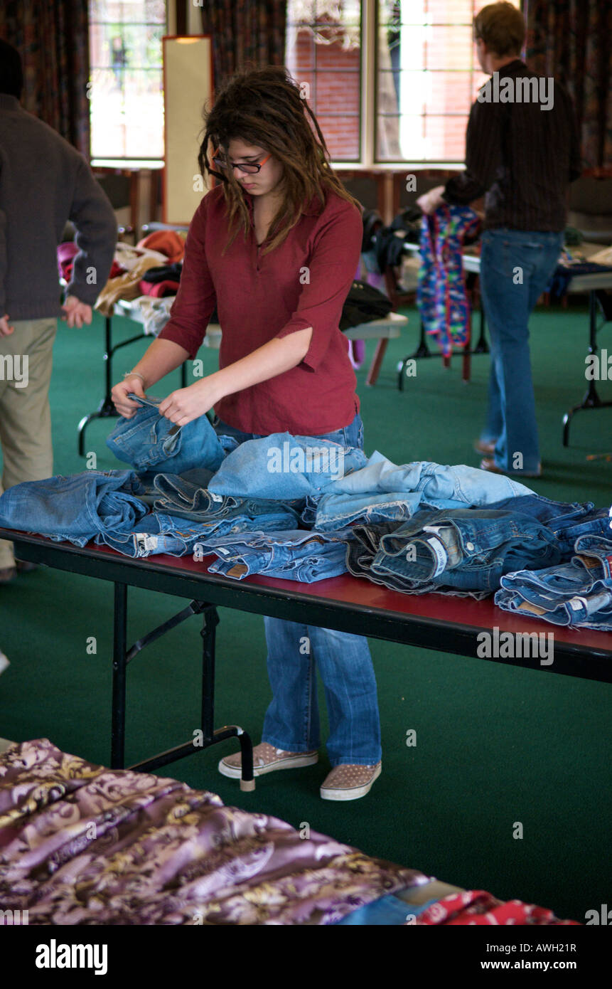 Eine junge Frau mit Dreadlock Haare inspiziert ein paar Denimjeans in einer Kleidung Swap an der University of Puget Sound in Tacoma, Stockfoto