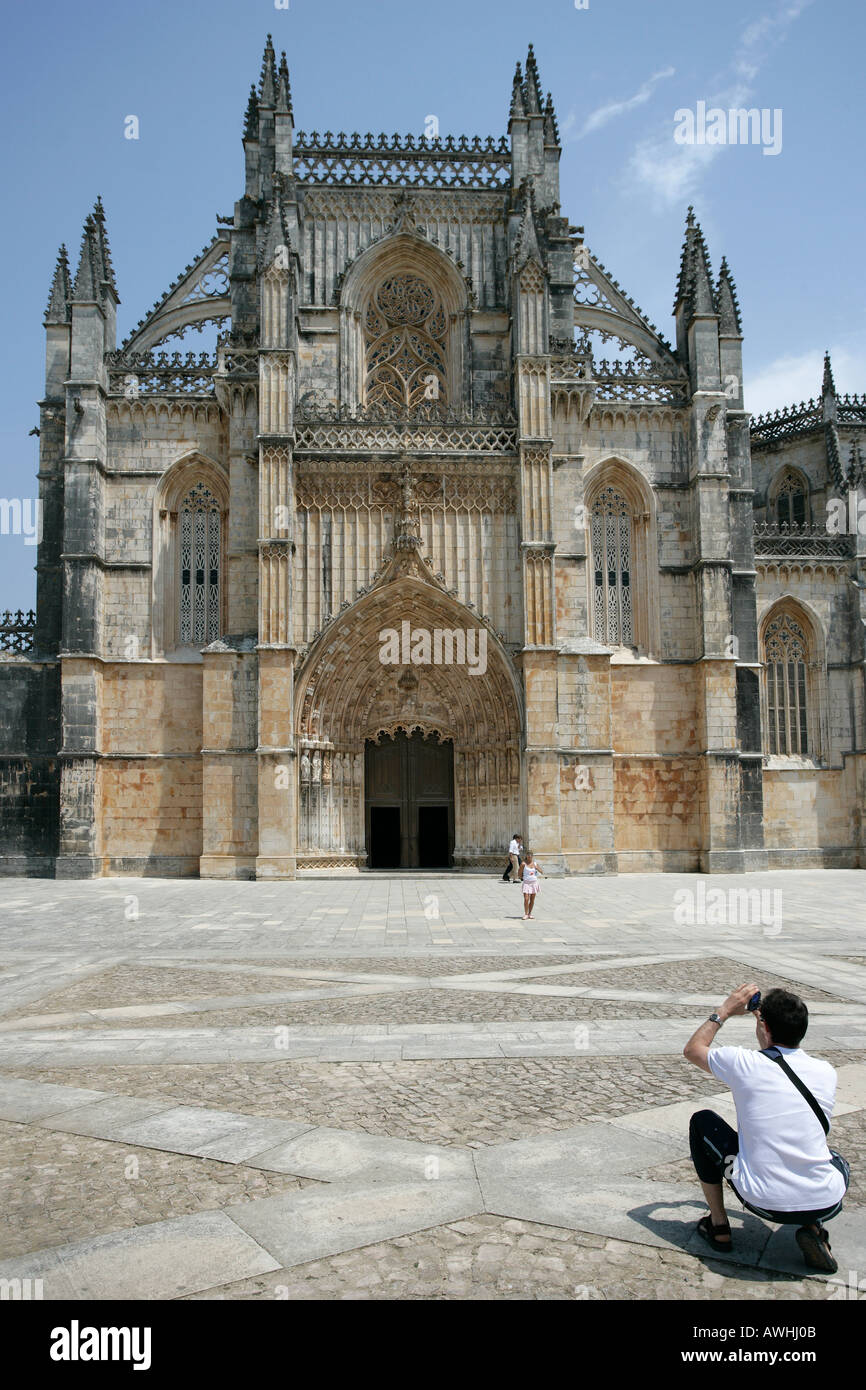 Ein Mann nimmt ein Snapshot-Foto von seiner Frau vor dem prunkvollen Kloster Batalha Portugal. Stockfoto