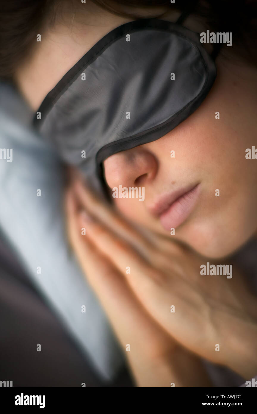 Frau schläft mit Eyemask und Händen unter ihr Gesicht Stockfoto