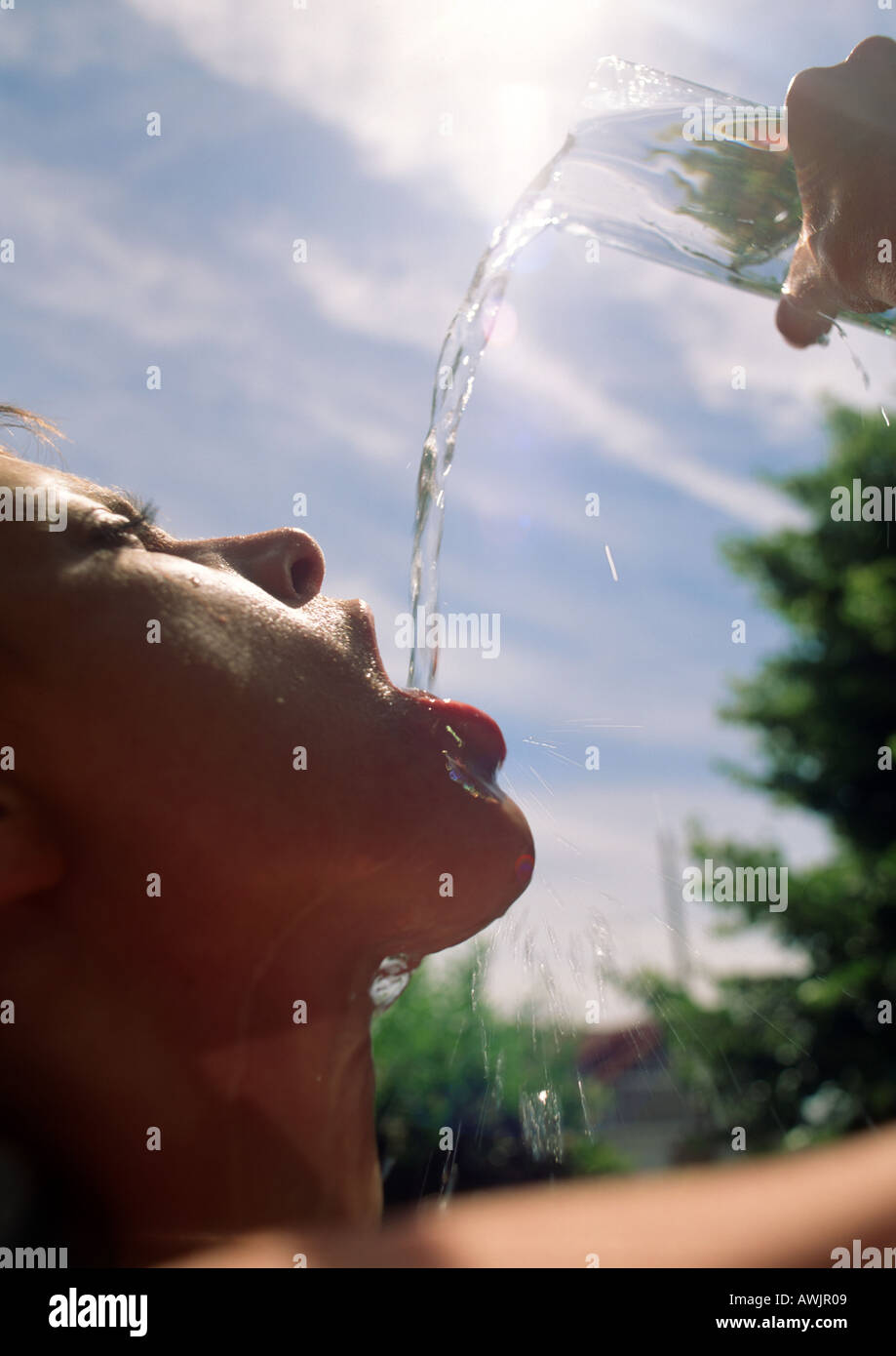 Frau gießt Wasser in Mund unter Sonne Stockfoto