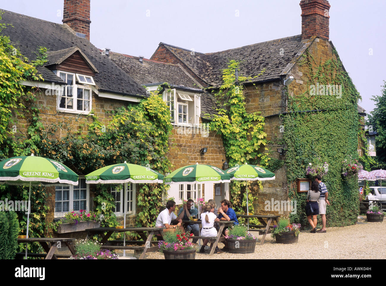 Lyddington Leicestershire Rutland Menschen essen trinken vor englischen Country Pub England UK Tabellen Menü lesen Sonnenschirme Stockfoto