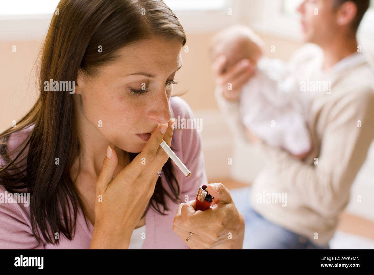 Mutter Rauchen, während Vater Baby beruhigt Stockfoto