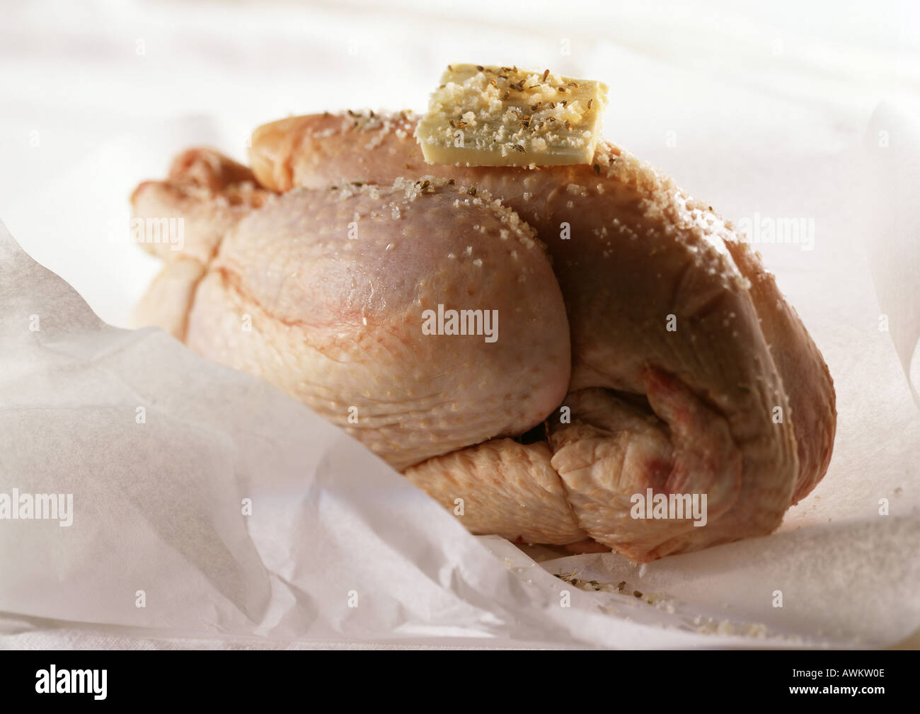 Ganze rohe Huhn und mit Stückchen Butter obendrauf, auf Papier, close-up Kochen Stockfoto