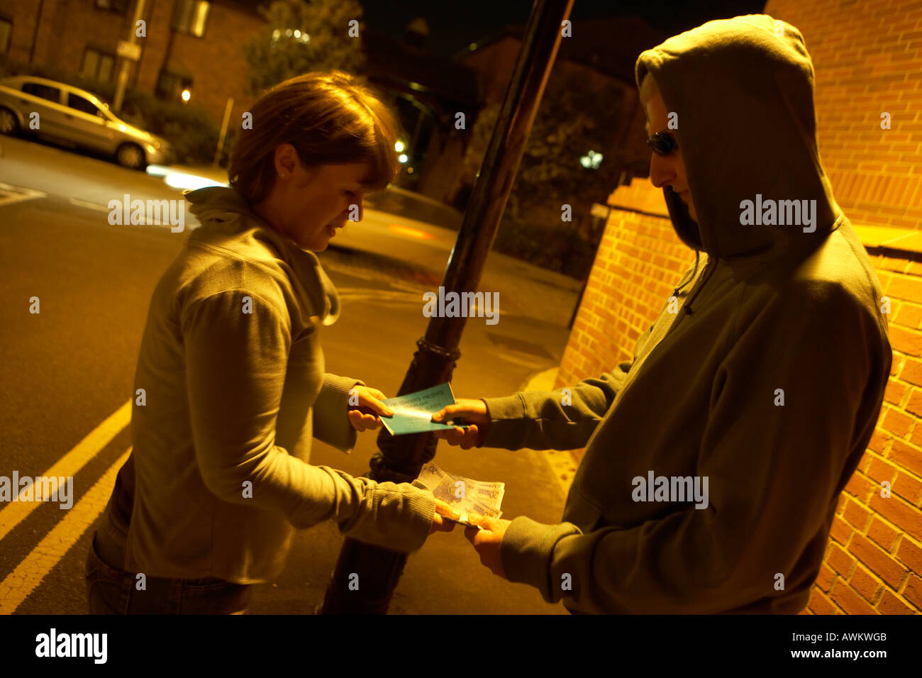 Junge Dame übergibt ein Ticket Tout unter einer Straßenlaterne in der Nacht die durch Modelle Geld für tickets Stockfoto