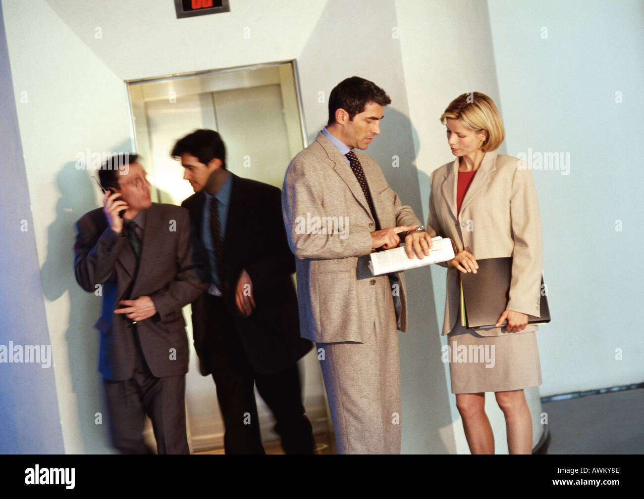 Geschäftspartnern vor Aufzug, Mann blickte auf seine Uhr Stockfoto