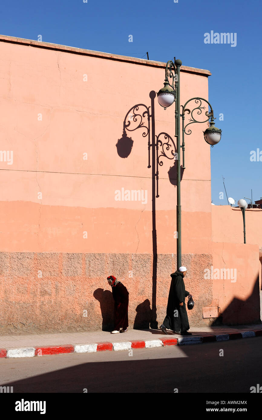 Ältere Männer und Frauen, die in entgegengesetzte Richtungen auf einem Bürgersteig im historischen Medina Viertel, Marrakesch, Marokko, Afrika Stockfoto