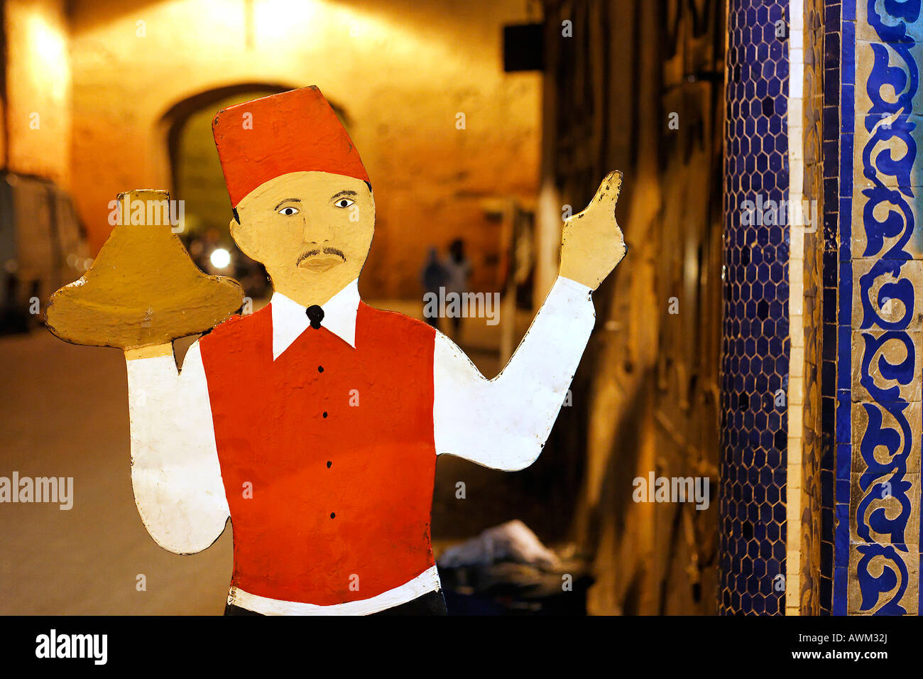 Kartonausschnitt eines Kellners, der einen fes trägt, der Tajine vor einem Restaurant im historischen Medina-Viertel, Marrakesch, M serviert Stockfoto