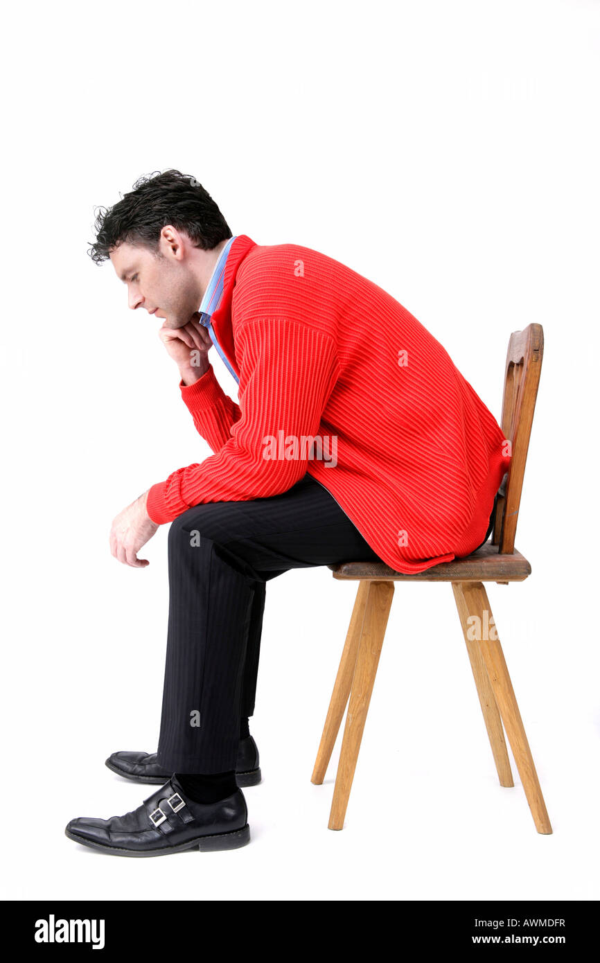 Mann trägt rote Jacke sitzt auf einem alten hölzernen Stuhl Stockfoto