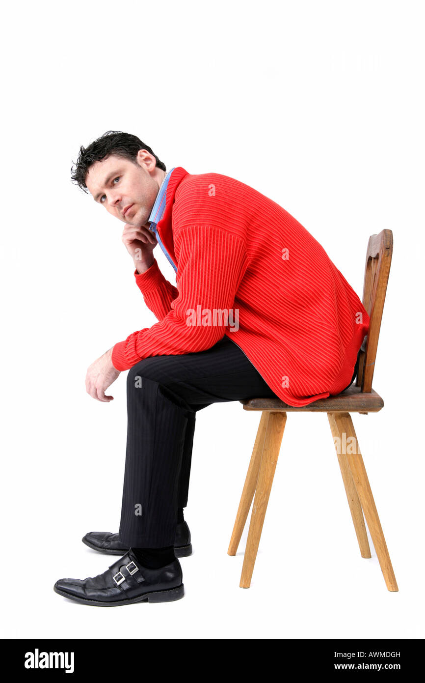 Mann trägt rote Jacke sitzt auf einem alten hölzernen Stuhl Stockfoto