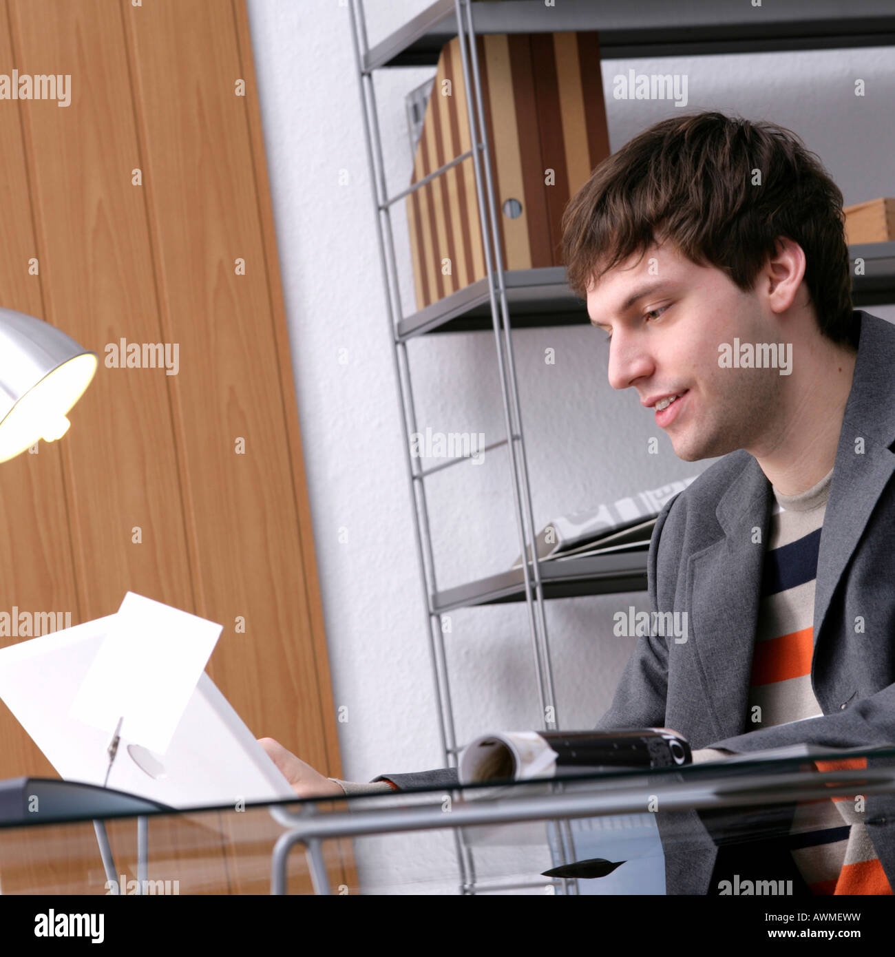 Junger Mann sitzt an einem Schreibtisch in einer guten Stimmung Stockfoto