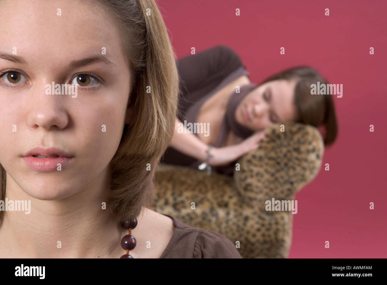 Zwei Mädchen, Pre-Teens, Teenager, man schläft auf einem Tiger-Print-Sofa mit den anderen im Vordergrund Stockfoto