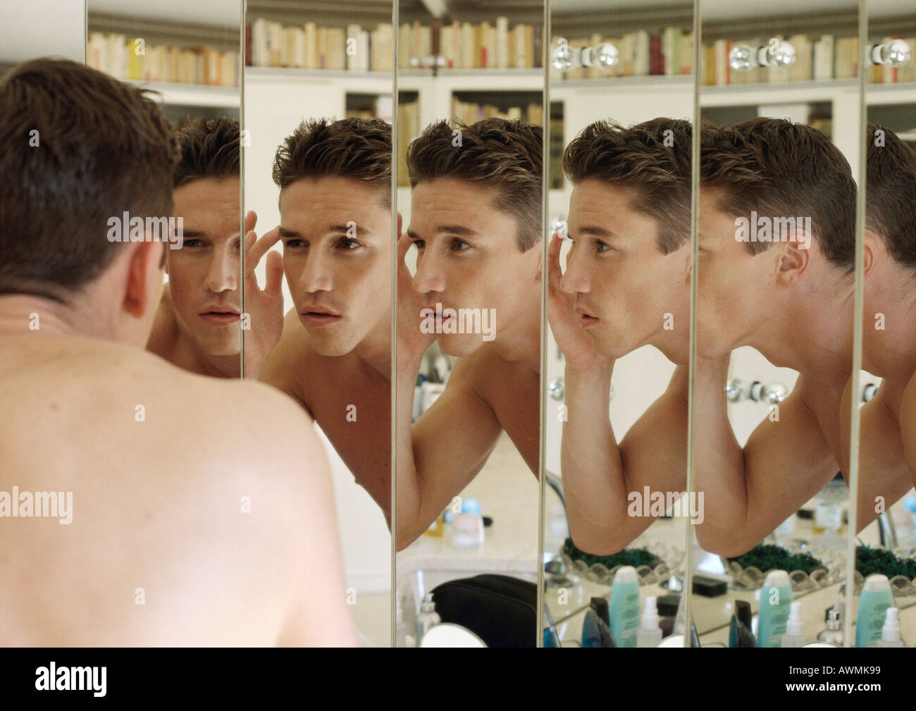 Mann berühren Augenbraue, Fokus auf mehrfache Reflexionen im Spiegel Stockfoto