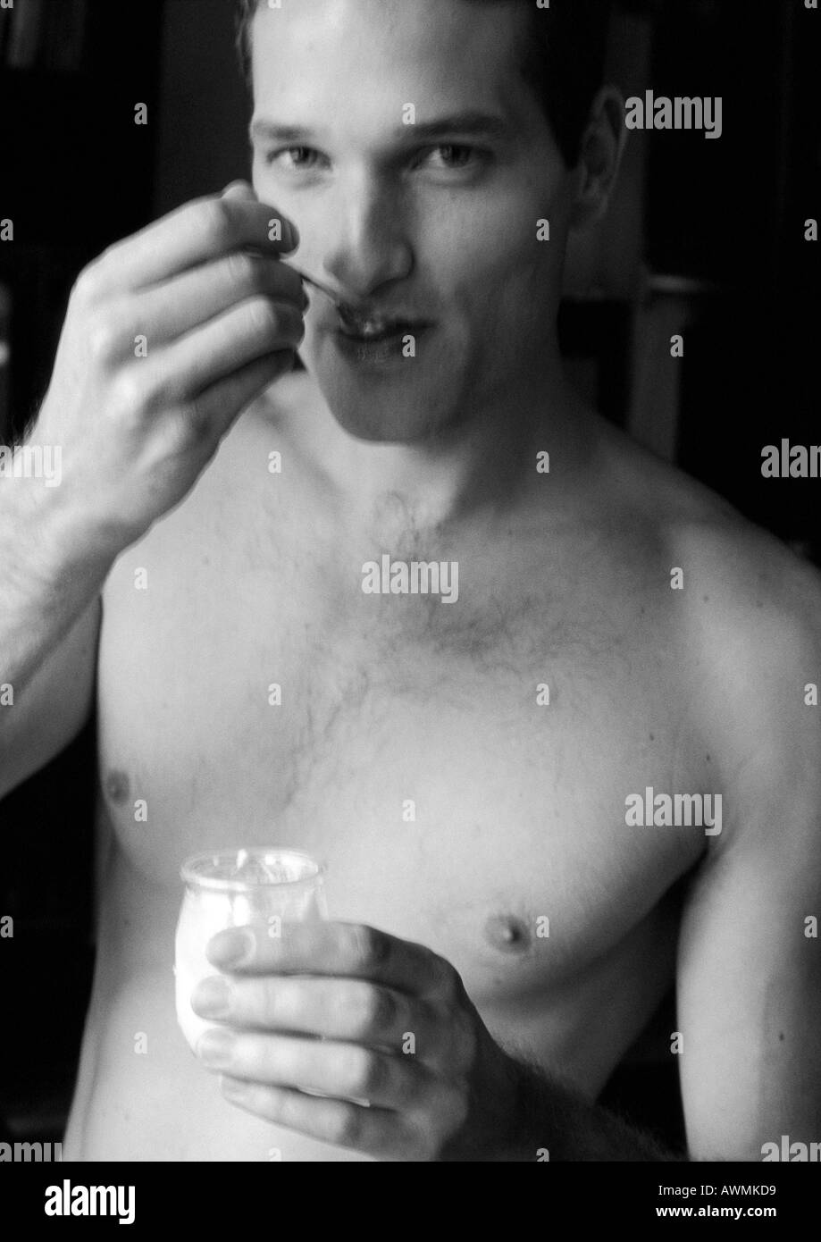 Mann isst Joghurt, Blick in die Kamera, b&w Stockfoto