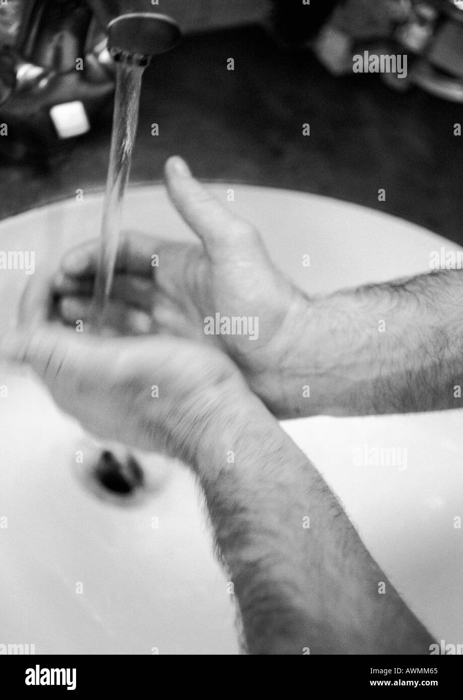 Die Hände des Mannes unter Wasserhahn, verschwommen, b&w Stockfoto