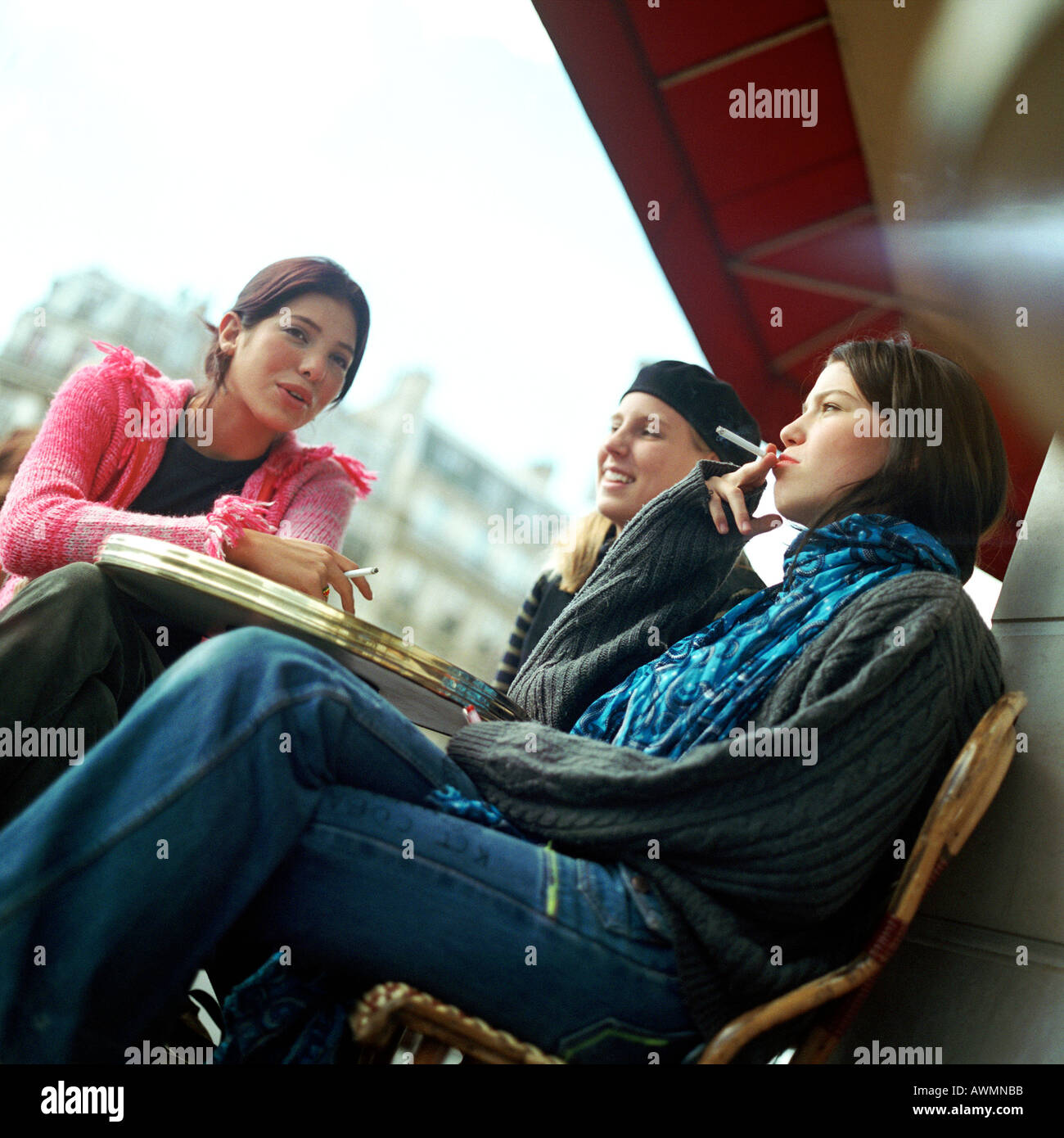 Drei Mädchen im Teenageralter sitzen im Caféterrasse, das Rauchen von Zigaretten, niedrigen Winkel Ansicht Stockfoto