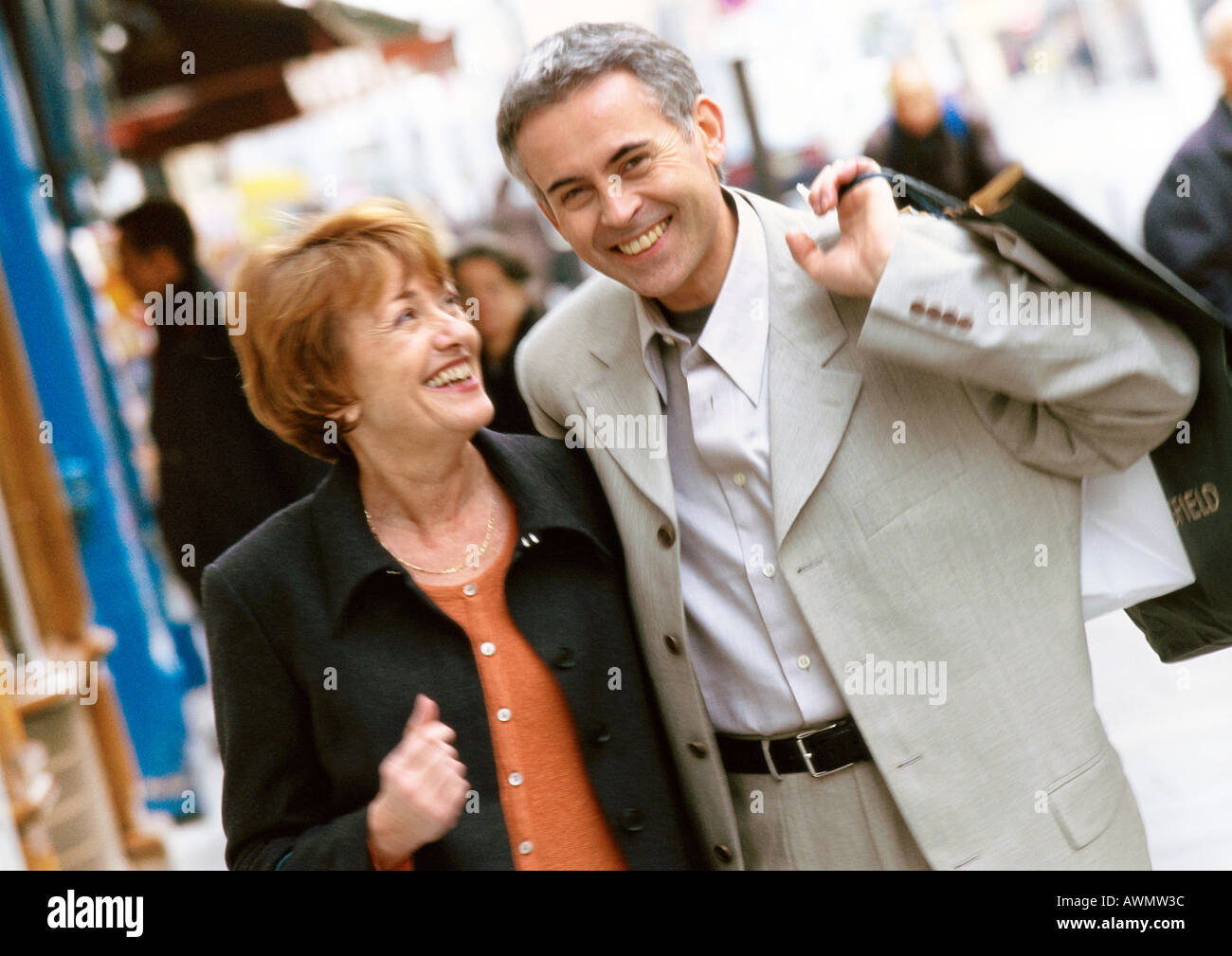 Mann und Frau zu Fuß zusammen, Mann, der Shopping-Tasche über die Schulter hält Stockfoto