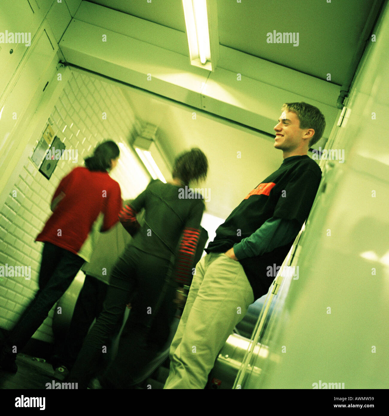 Junger Mann in u-Bahn-Korridor, Seitenansicht, Menschen gehen, hintere Ansicht im Hintergrund stehen Stockfoto