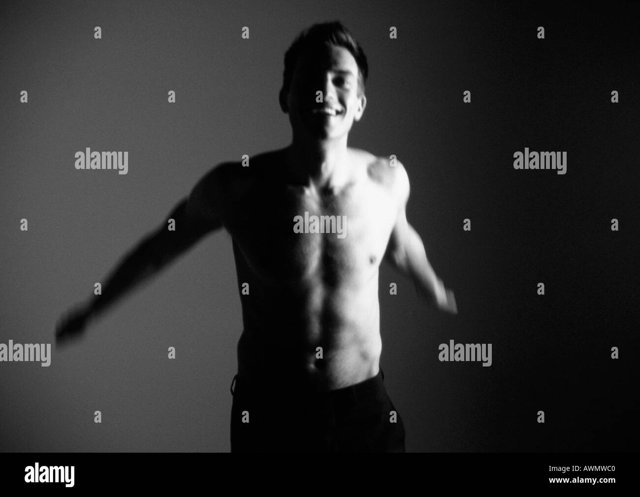 Drilliche Mann erreichen Arme nach hinten und lächelnd, verschwommen, schwarz und weiß. Stockfoto