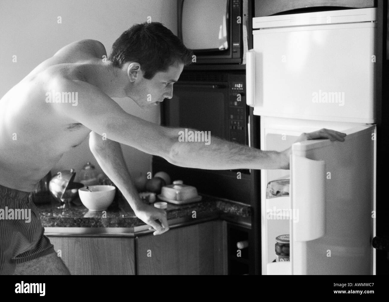 Mann mit Unterwäsche, biegen um im Kühlschrank, Seitenansicht, schwarz und weiß sehen. Stockfoto