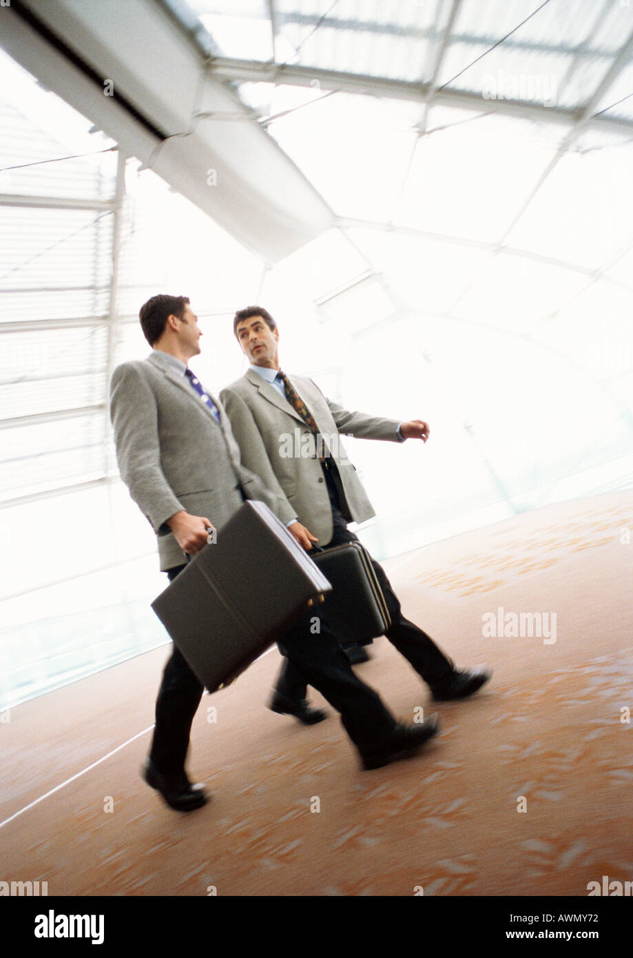 Geschäftsleute gehen zusammen mit Aktentaschen, drinnen. Stockfoto