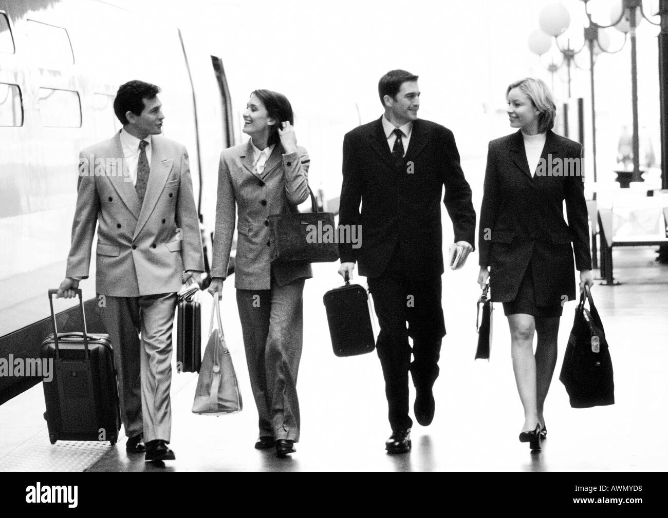 Geschäftsleute, die zu Fuß mit Gepäck neben Zug, Ganzkörperansicht, b&w. Stockfoto