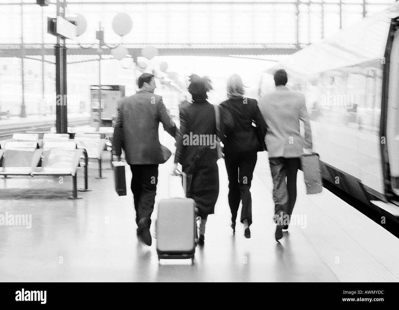 Gruppe von Geschäftsleuten, die zu Fuß auf Bahnsteig, Rückansicht, b&w. Stockfoto