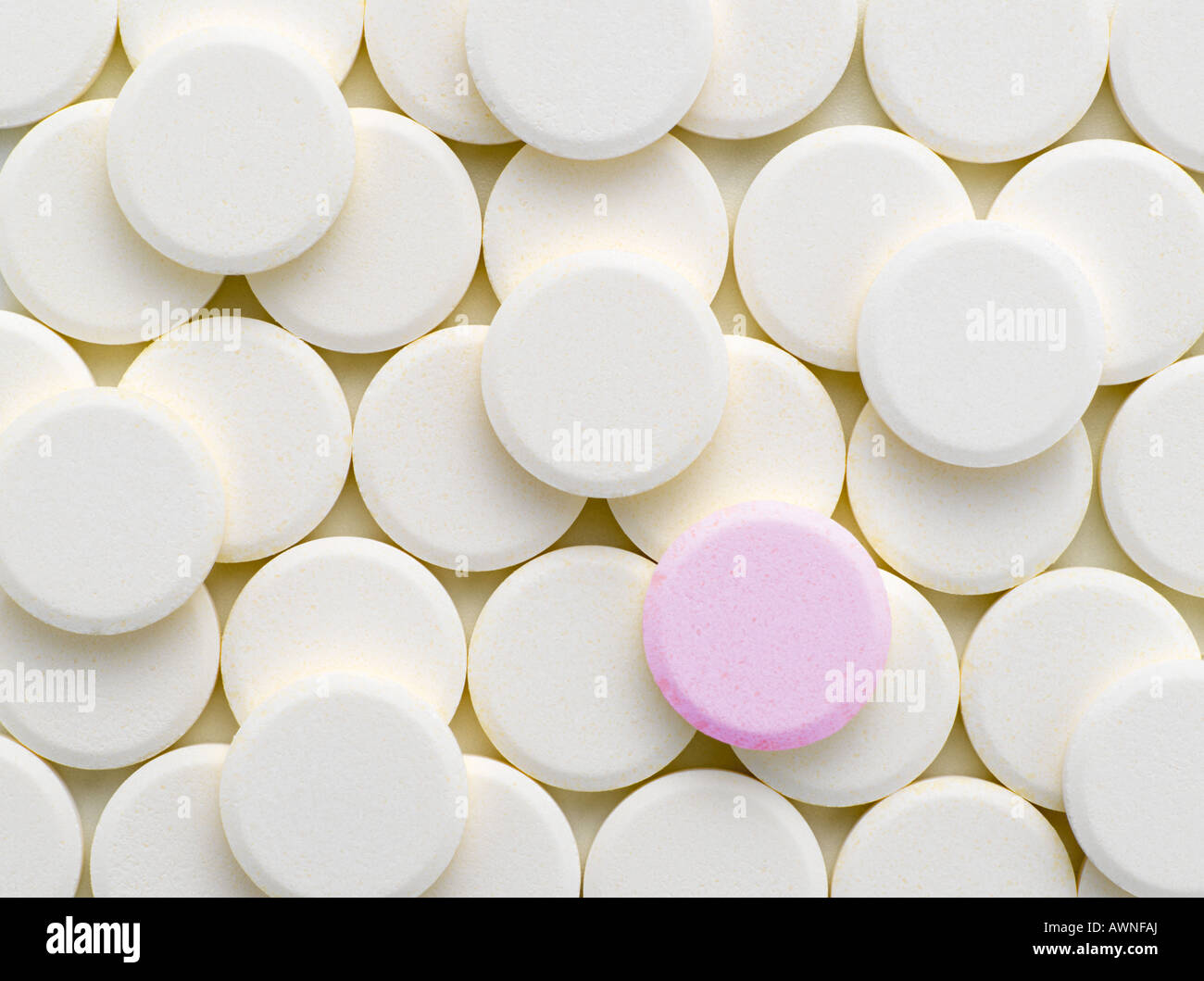 Eine rosa Tablette unter weißen Tabletten Stockfoto