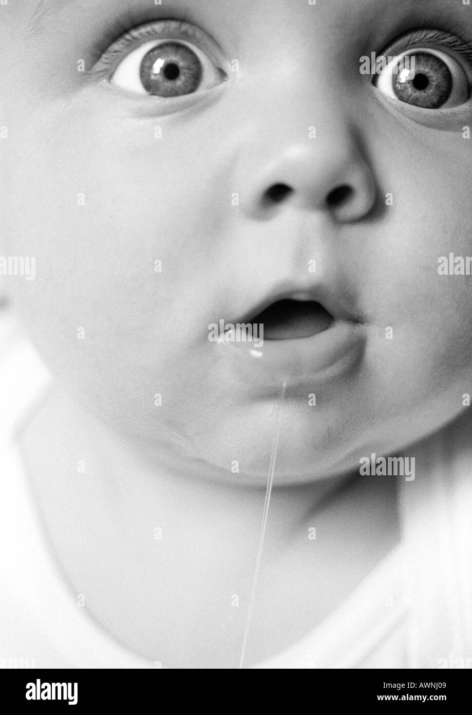 Baby mit offenem Mund, sabbern, weit geöffneten Augen Blick aus Rahmen, extreme close-up, B&W. Stockfoto
