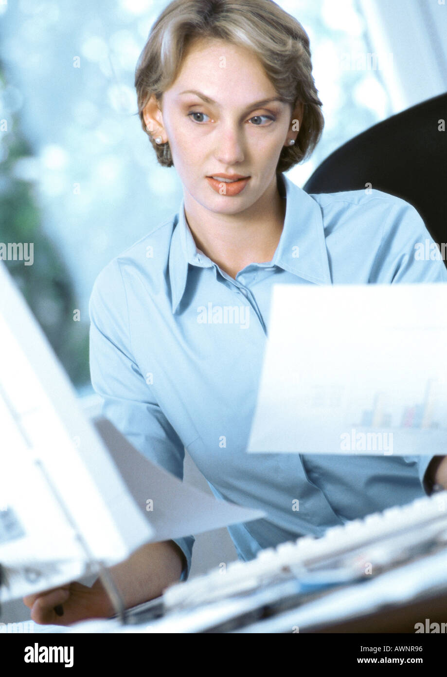 Geschäftsfrau hält Dokumente, Blick auf computer Stockfoto