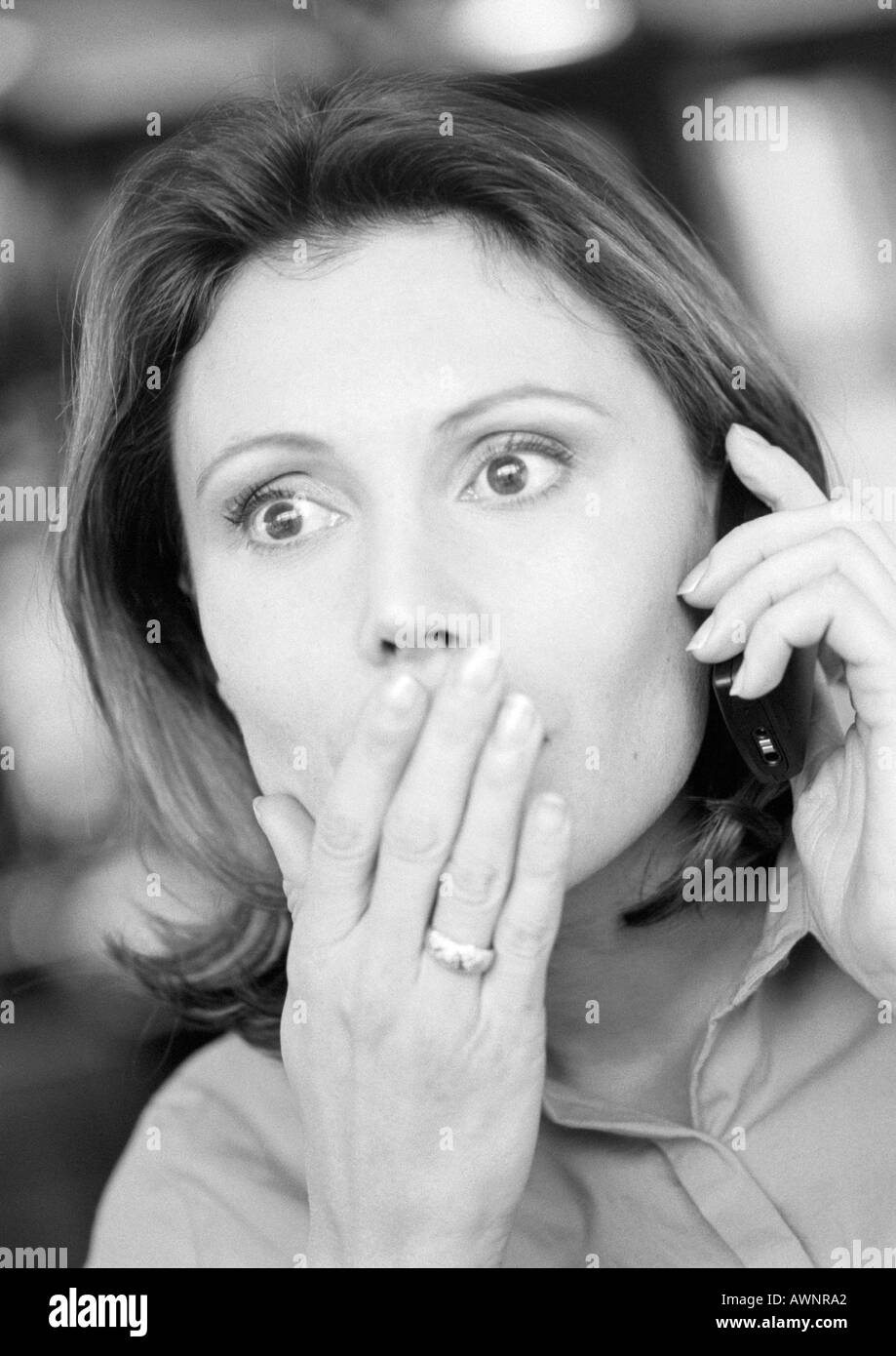 Frau mit Handy, Hand über Mund, Nahaufnahme, B&W Stockfoto