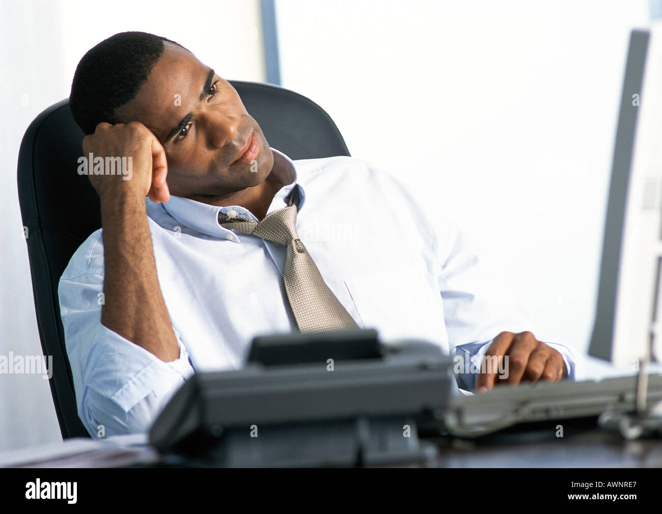 Geschäftsmann, sitzen am Schreibtisch, Kopf gelehnt auf Seite Stockfoto
