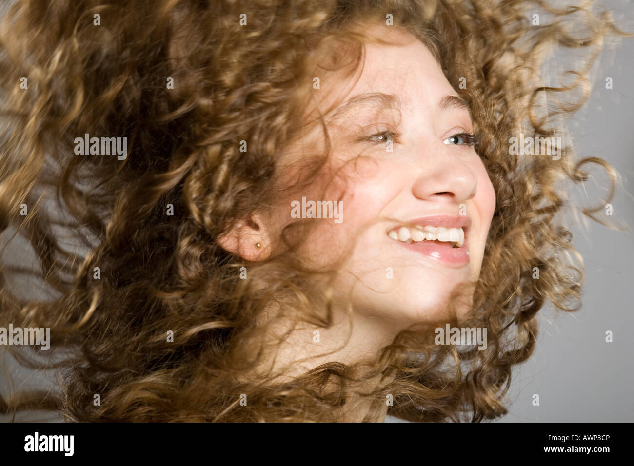 Junge Frau, ihr langes lockiges Haar durch die Luft fliegen Stockfoto