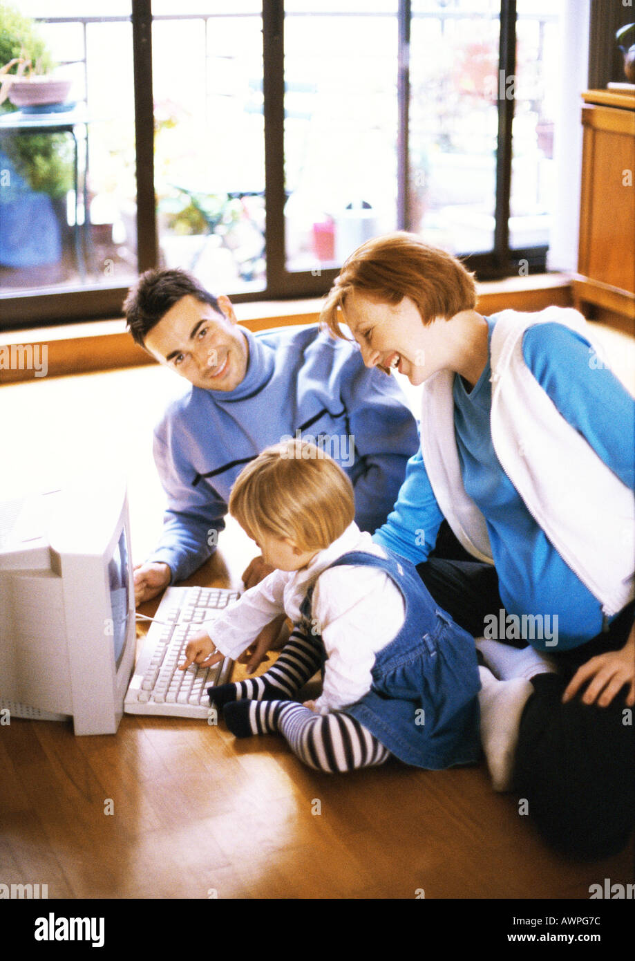 Schwangere Frau und Mann am Boden mit Kind, die Computer-Tastatur zu berühren Stockfoto