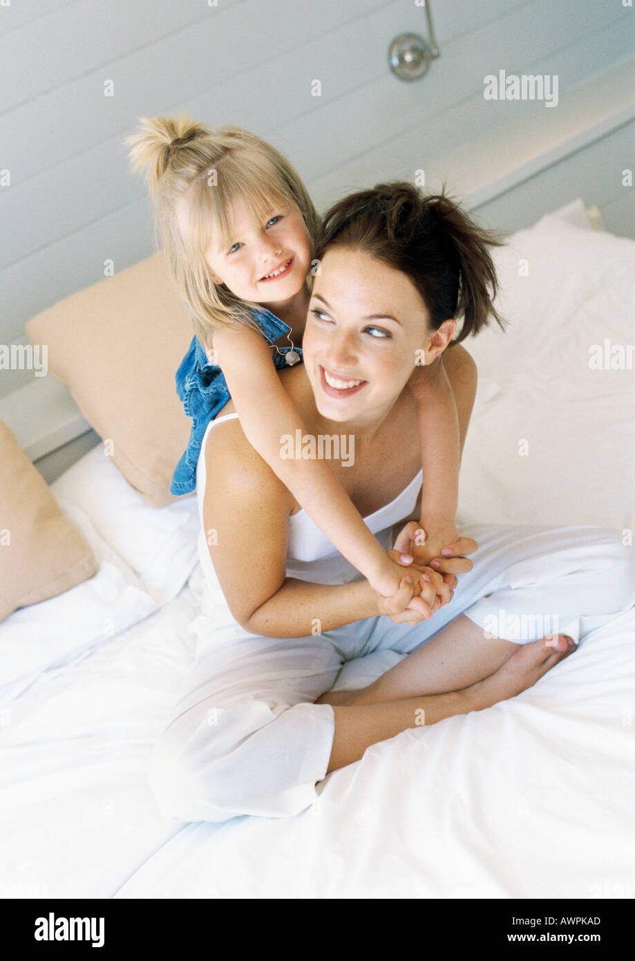 Mutter sitzt auf Bett, halten Mädchen auf Rückseite Stockfoto
