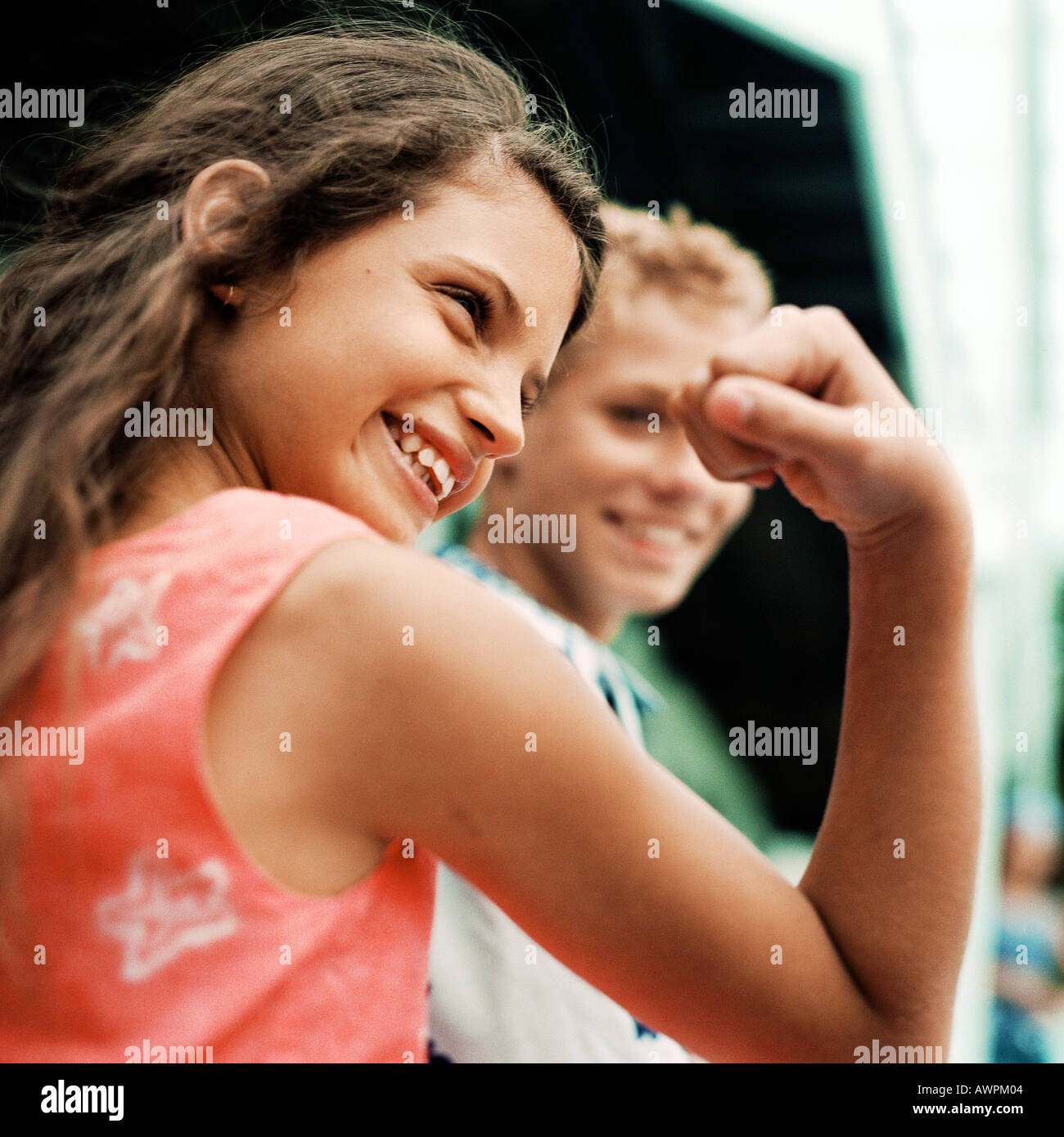 Lächelnde Mädchen biegen Armmuskeln, junge im Hintergrund, Stockfoto