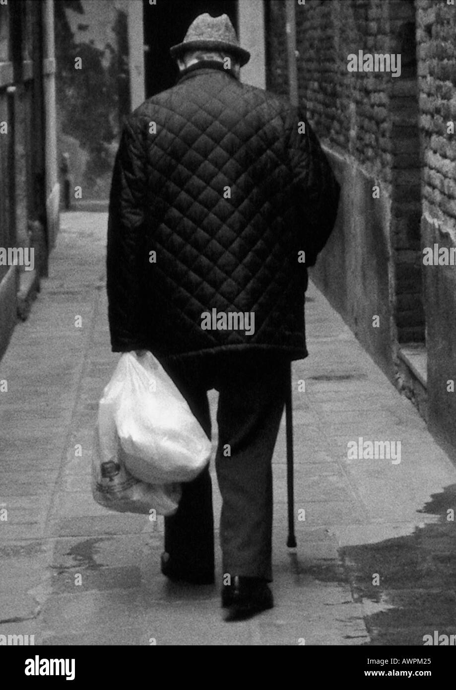 Mann mit Stock, mit Einkaufstüten, Rückansicht, b&w Stockfoto