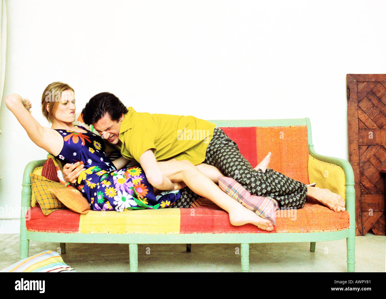 Paar auf Sofa, Mann auf Frau, Frau mit Arm bereit, zuzuschlagen stürzen Stockfoto