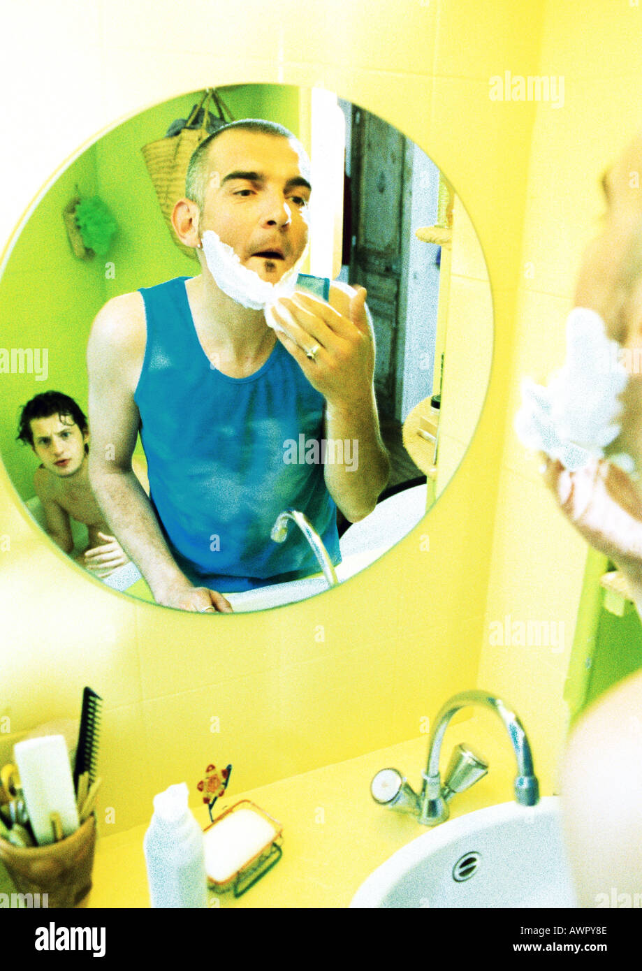Zwei Männer im Bad, eine Rasur, in Wanne, Reflexion im Spiegel. Stockfoto