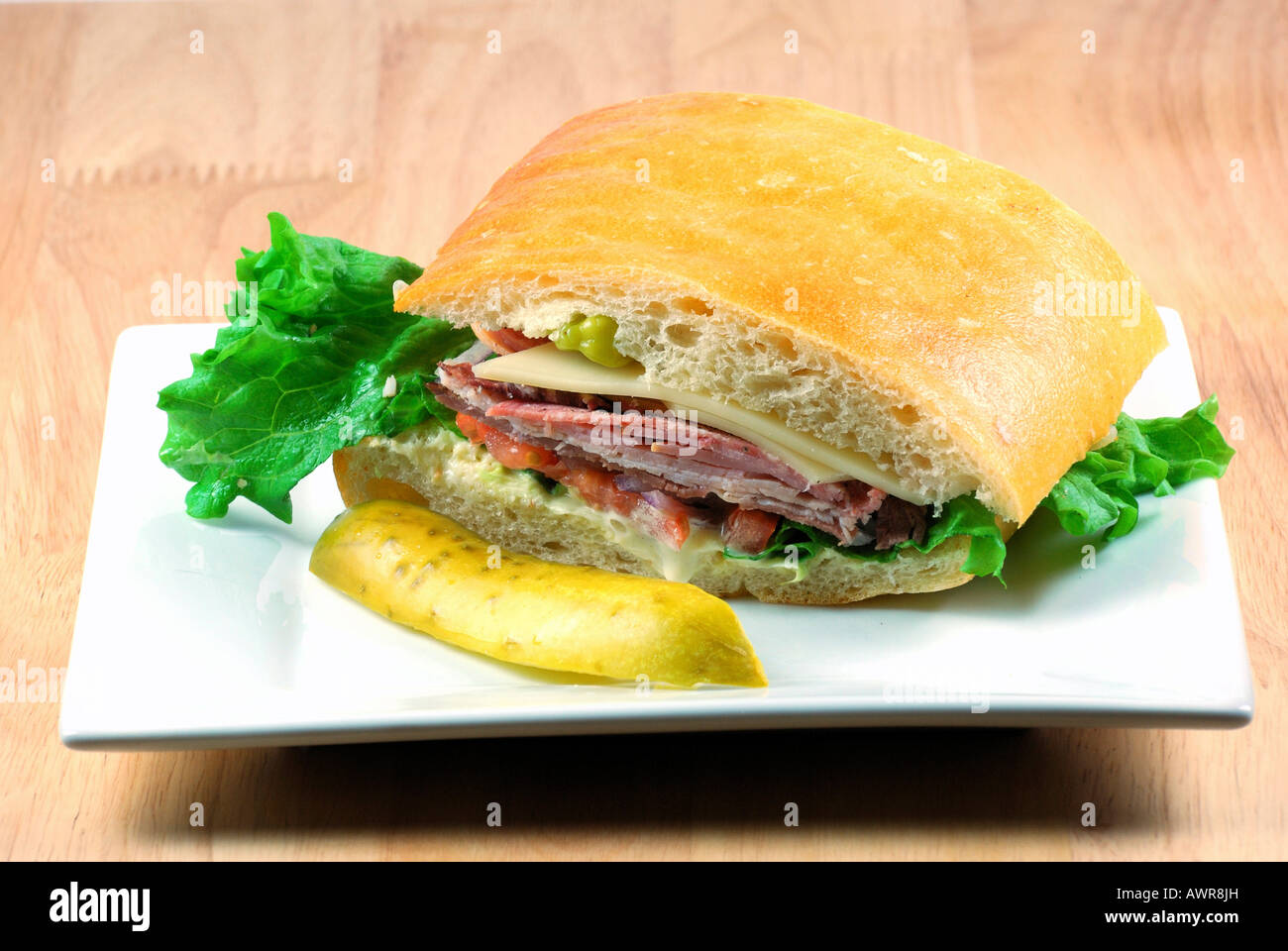 Sandwich auf einem weißen Teller mit einer Essiggurke Stockfoto