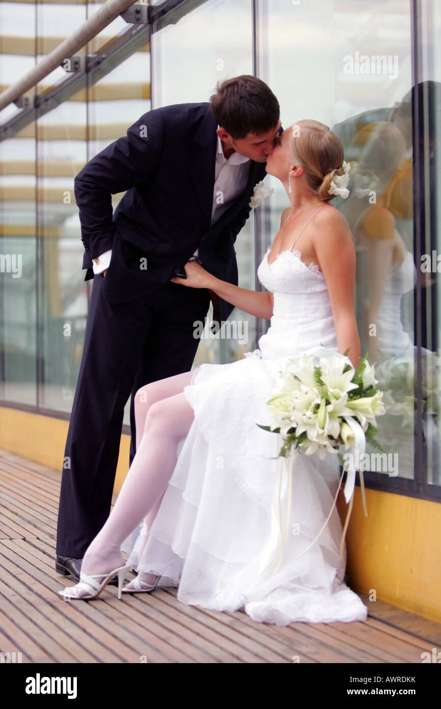 Lächelnde Braut in traditionellen weißen Brautkleid Bräutigam küssen Stockfoto