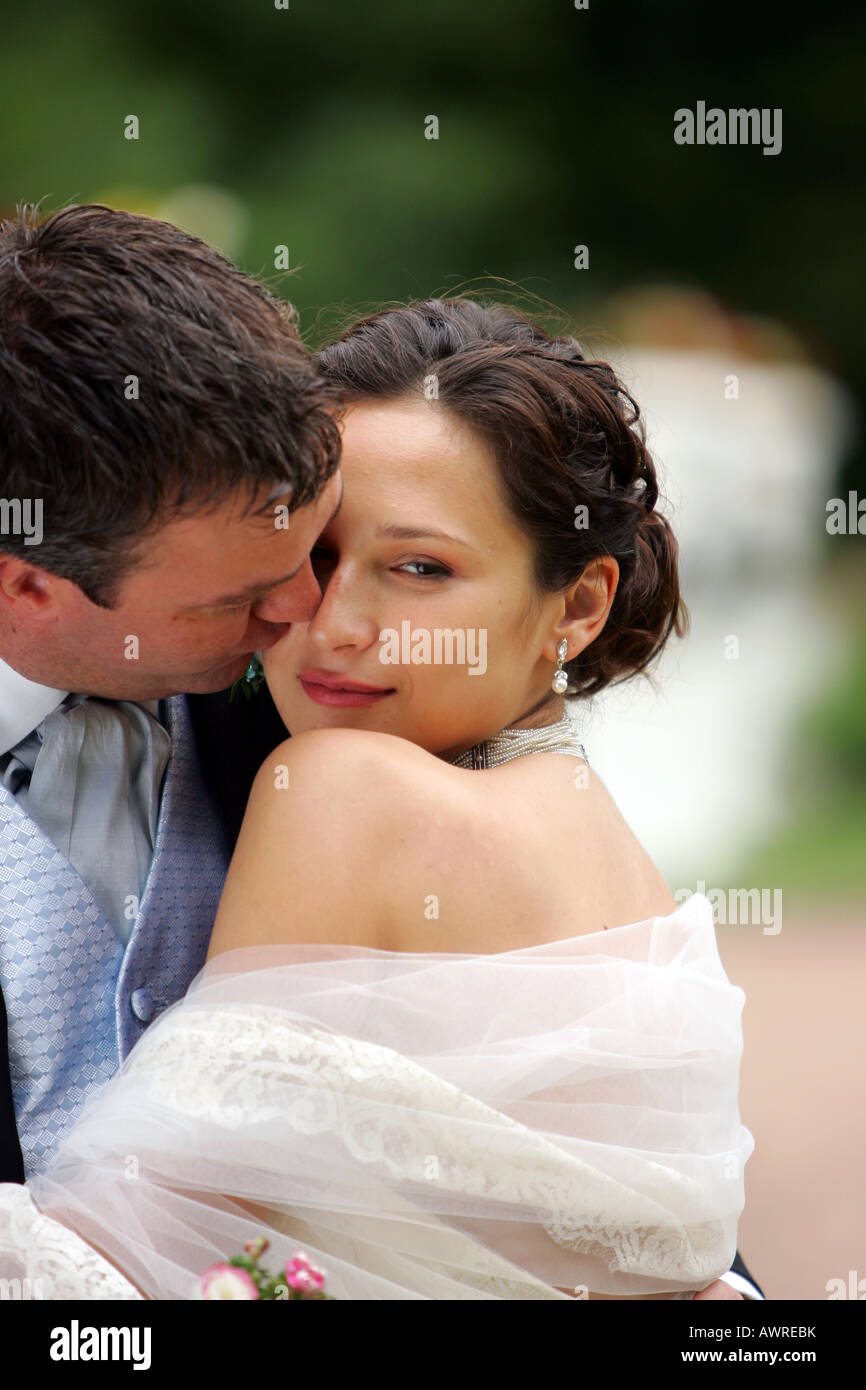 Lächelnde Braut in traditionellen weißen Brautkleid Bräutigam küssen Stockfoto