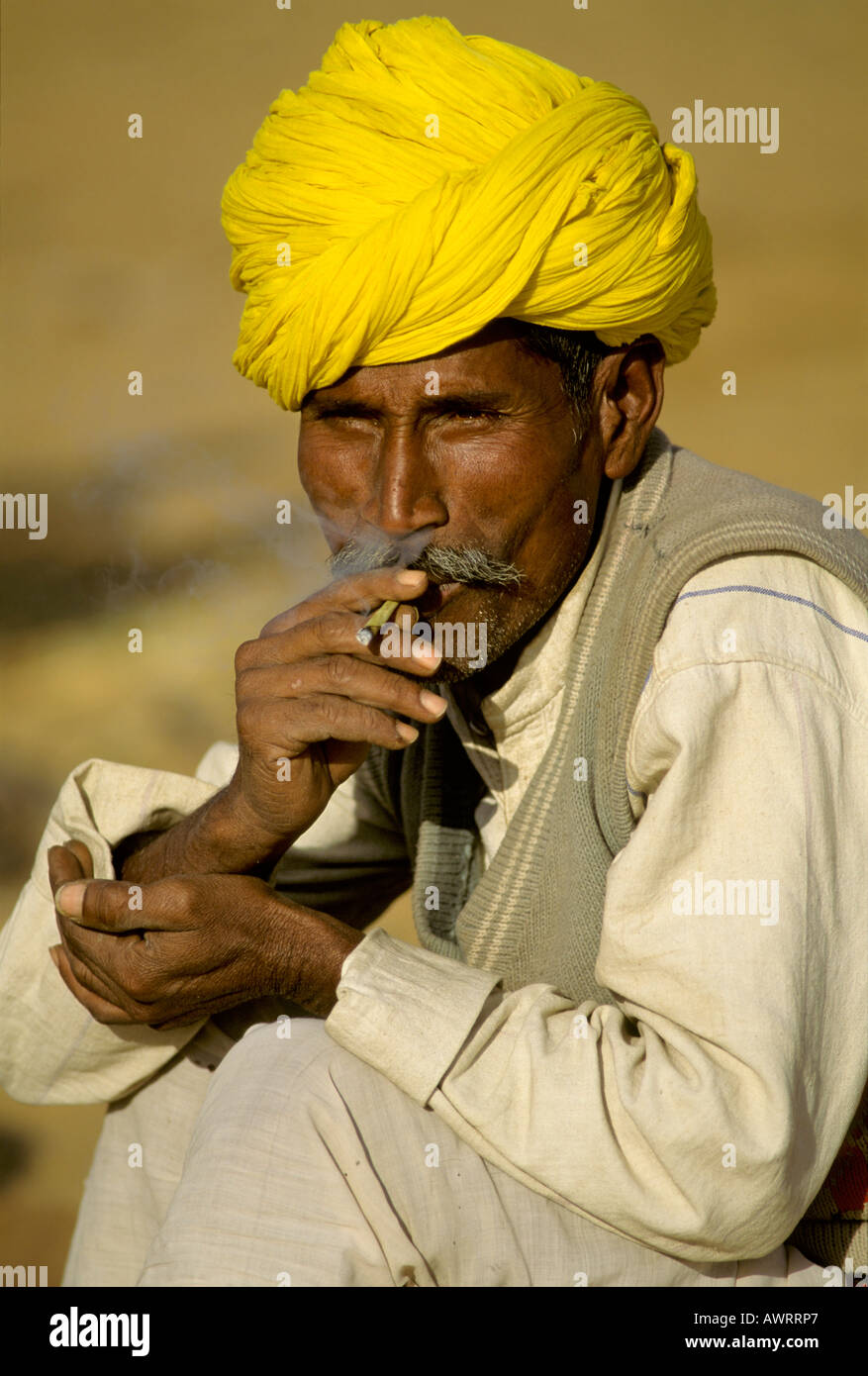 Mann mit gelber Turban Rauchen einer Zigarette Bidi, Pushkar, Rajasthan, Indien Stockfoto