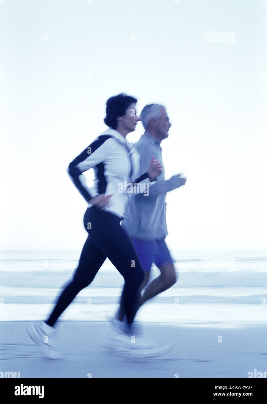 Reifer Mann und Frau laufen am Strand, Seitenansicht Stockfoto