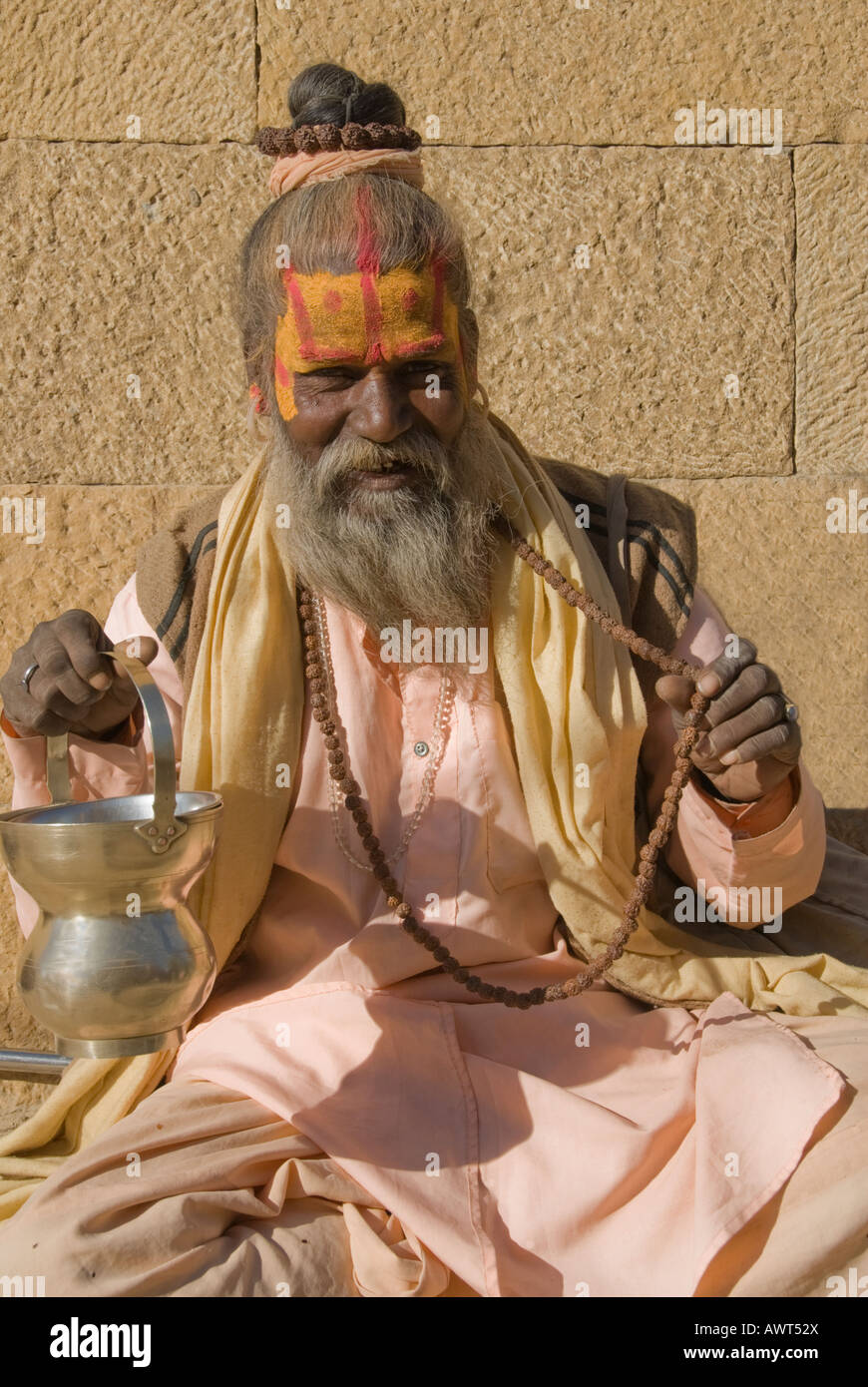 Porträt von einem älteren Sadhu mit Perlen und bronzene Schüssel gekleidet in Pastell Gewand in Jaisalmer, Rajasthan, Indien Stockfoto